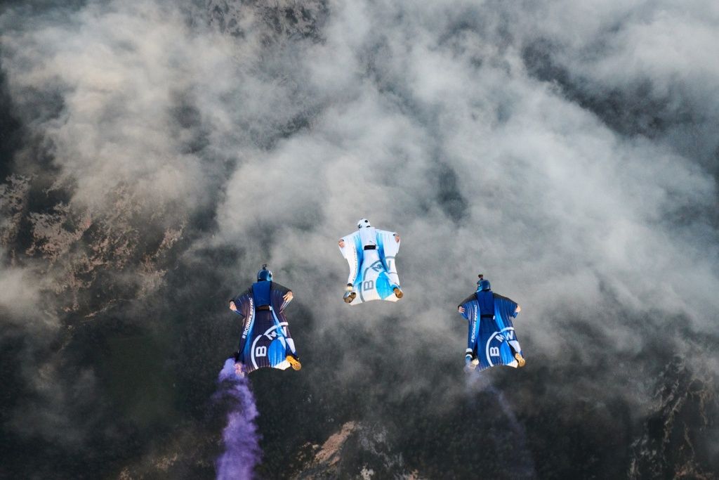 Three people flying with BMW Wingsuits.