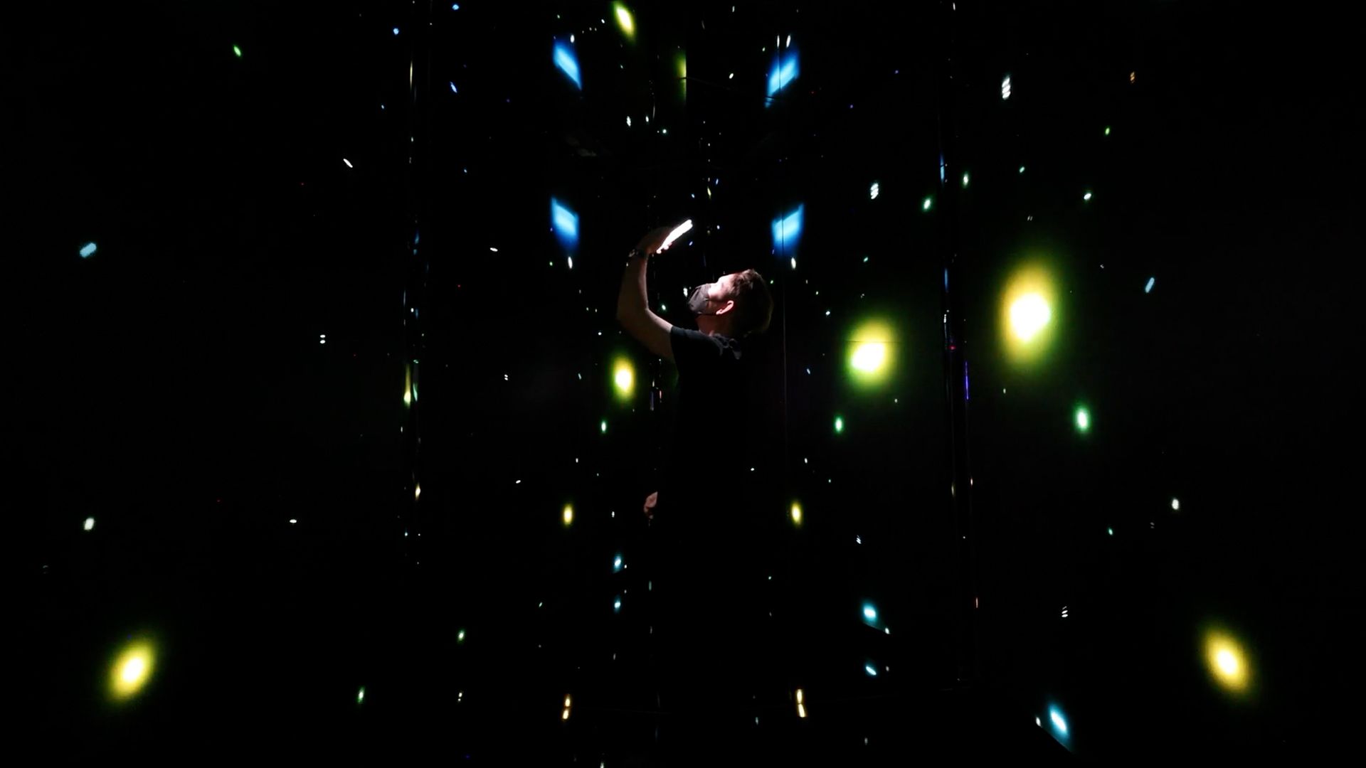 A visitor experiences the Infinity Room in solitude, immersed in interactive graphics.