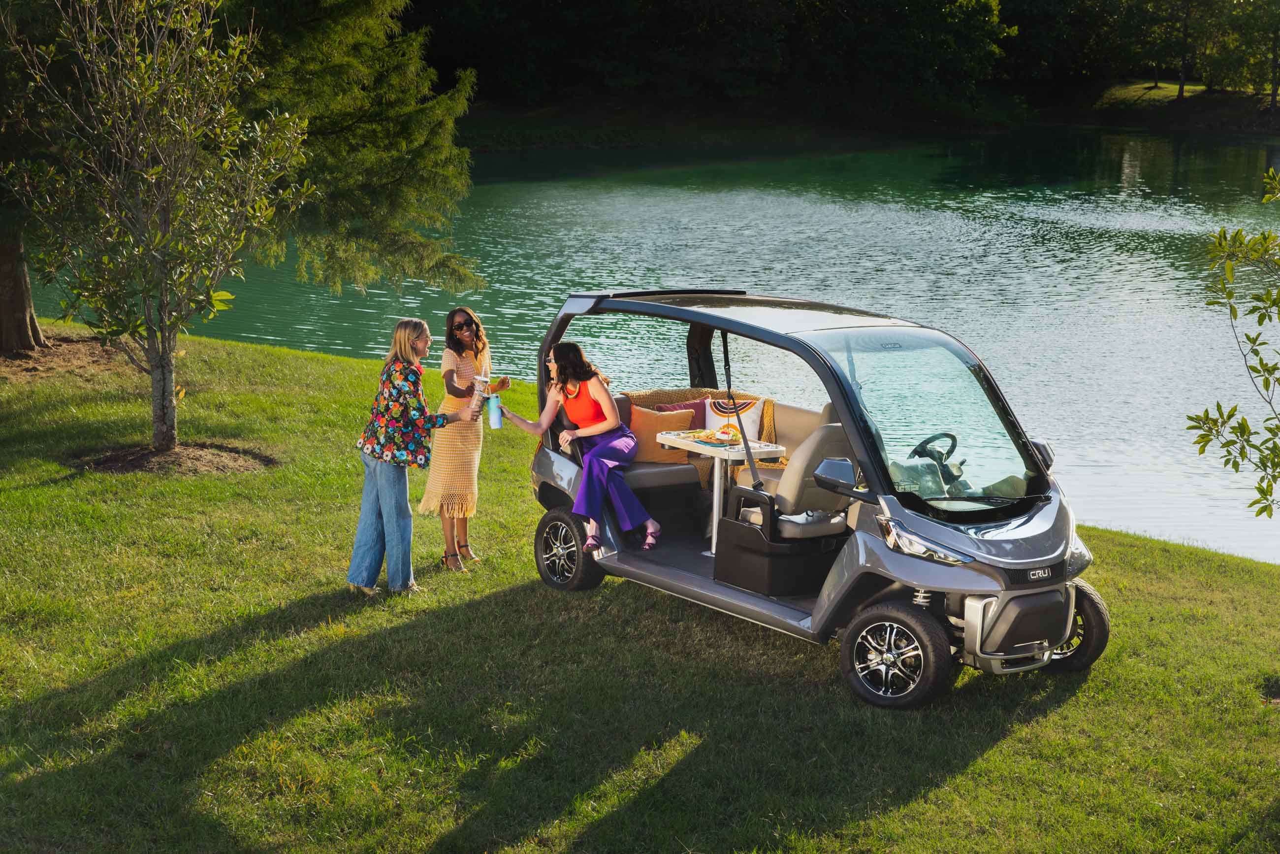 Friends enjoying a picnic by the lake, using the CRU Club Car as a social space.